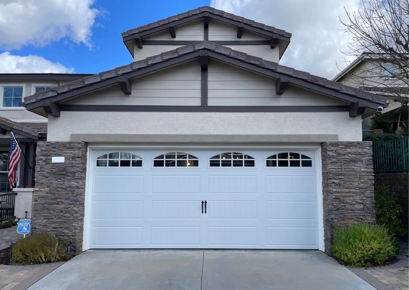 A white modern farmhouse with a large, dark gray carriage-style garage door and black-trimmed windows.